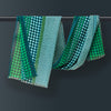 Soft and vibrant: Lightweight wool scarf adorned with blue and green polka dots, elegantly draped over a wooden pole.